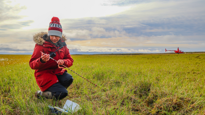 Person hunched down near a field of grass