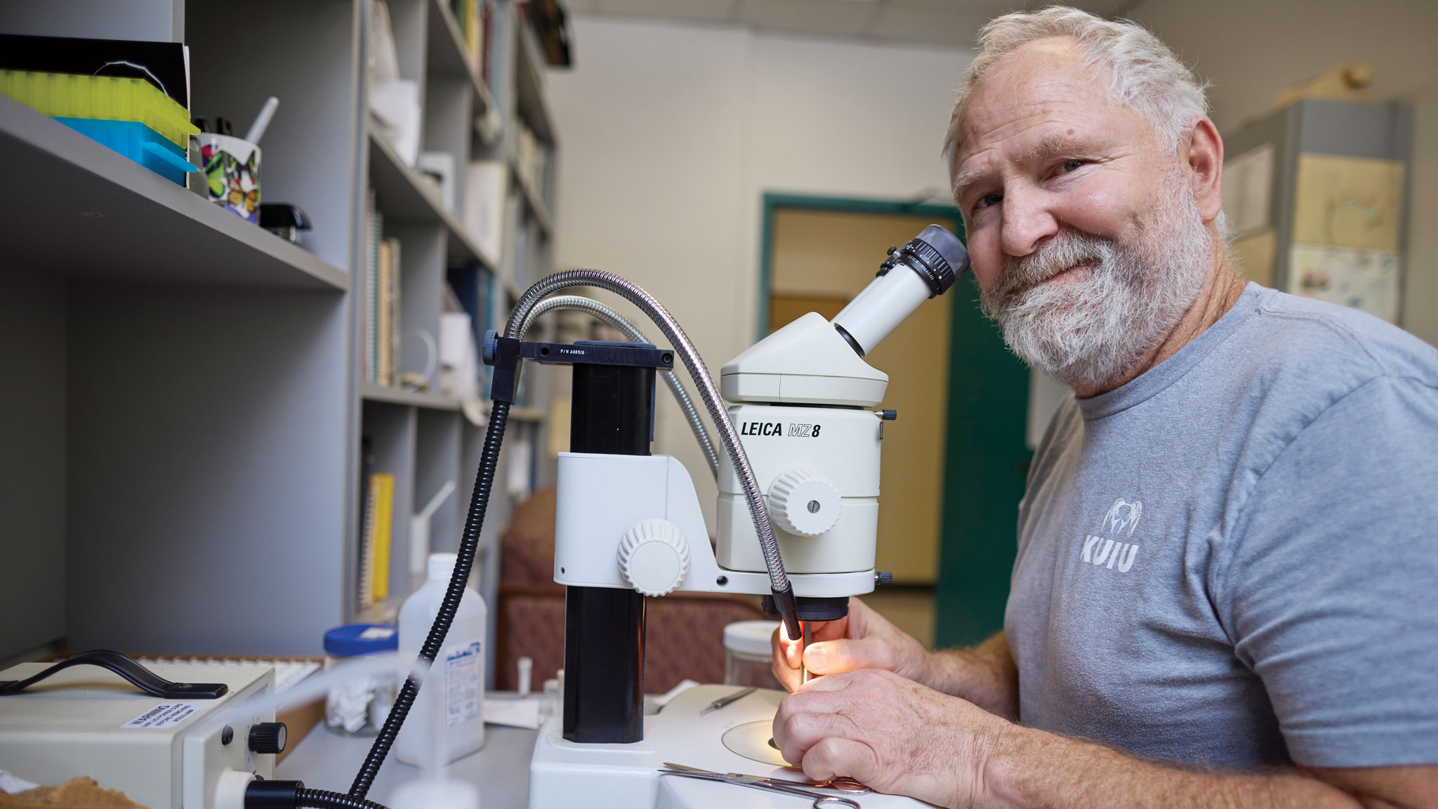 Man smiling next to his microscope