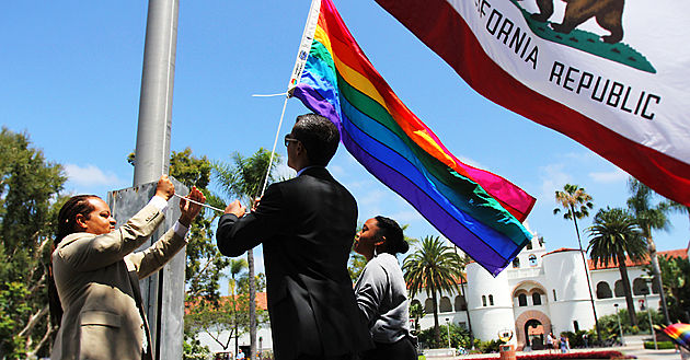 From left, Aaron Bruce, Cody Barbo and Channelle McNutt raise the rainbow flag.  Photo by Antonio Zaragoza.