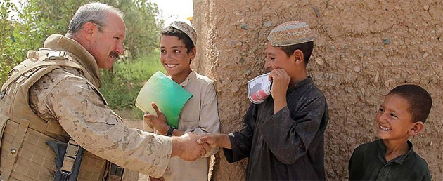 Petty Officer 2nd Class William Lowry, corpsman and Civil Affairs specialist with Regimental Combat Team 3, shakes hands with a local boy during a patrol in Helmand Province, Afghanistan, Aug. 2009.