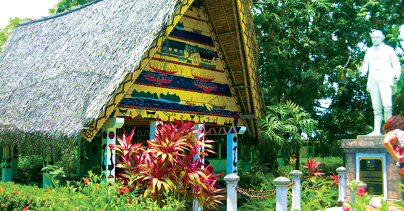 A traditional meeting house or bai at the entrance to Palau Community College. The statue is of Lebuu, the first Palauan scholar to study in England.