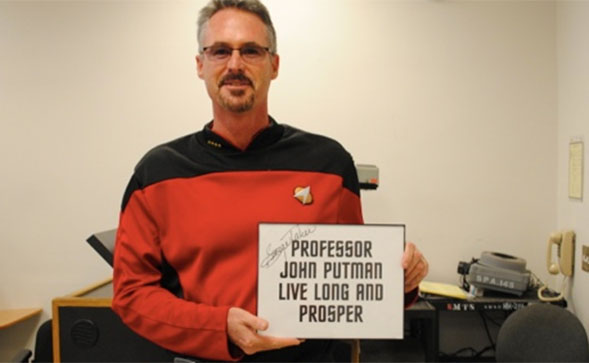 Professor Putman holding a signed card from George Takei i who played Lt. Sulu in the original Star Trek series.