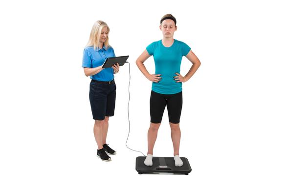 A trainer tests an athlete's balance on the BTrackS balance board.
