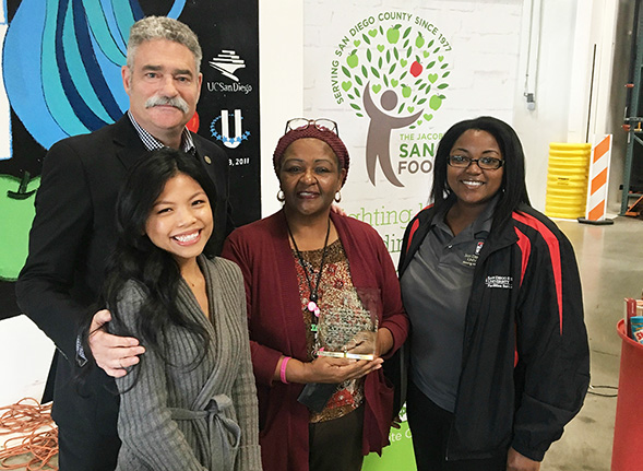 Benita Mann (center) holds the Community Partner Award from the Jacobs &amp; Cushman San Diego Food Bank.