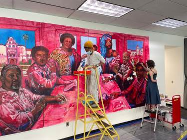 Sabrina Davidson (center) and Avia Ramm painted their mural on the first floor of the University Library Addition. Depicted in the mural are (clockwise from left) Charles Bell, E. Walter Miles, Shirley Weber, Henrietta Goodwin, Amber St. James, Joseph Johnson, Harold K. Brown.