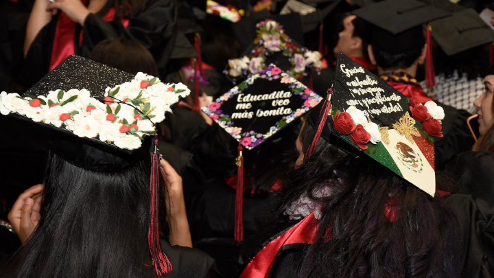 Image shows graduates in caps with color decorations