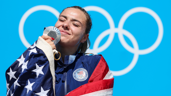 Drapped in an American flag, Nevin Harrison celebrates on the podium with her silver medal at the 2024 Olympic Games in Paris