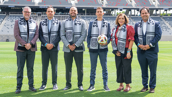 Members of SDSU and San Diego FC leadership pose for a photograph on the field at Snapdragon Stadium