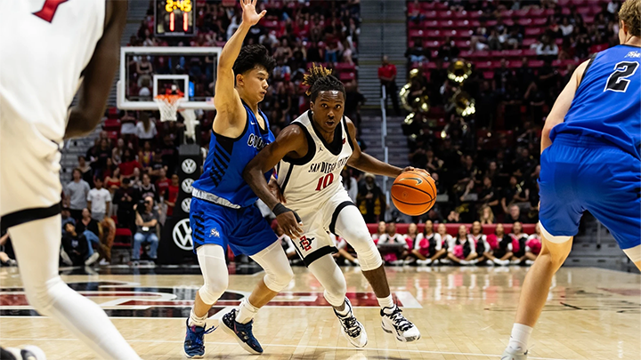 SDSU basketball player makes a play to the basketball with a defender guarding him closely