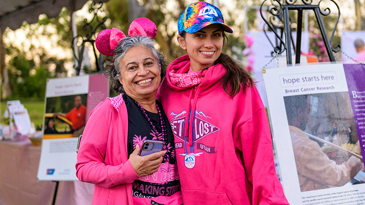 Participants dressed in pink racing wear pause during the Making Strides event to smile for the camera.