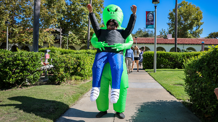 A student in an alien costume poses for a photo at SDSU.