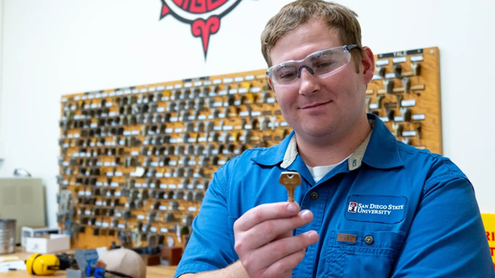 Locksmith apprentice Brenden Schroeder inspects a newly fabricated key in the lock shop. \