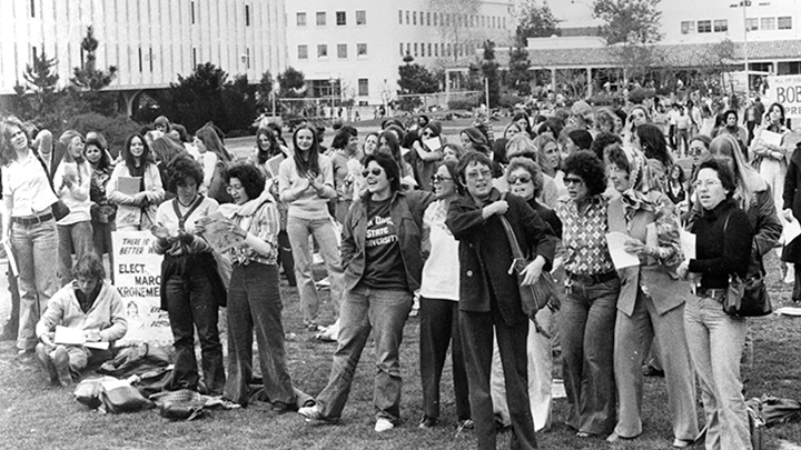 A black and white photo taken in 1976 shows several SDSU students gathering on campus for the Susan B. Anthony Celebration.