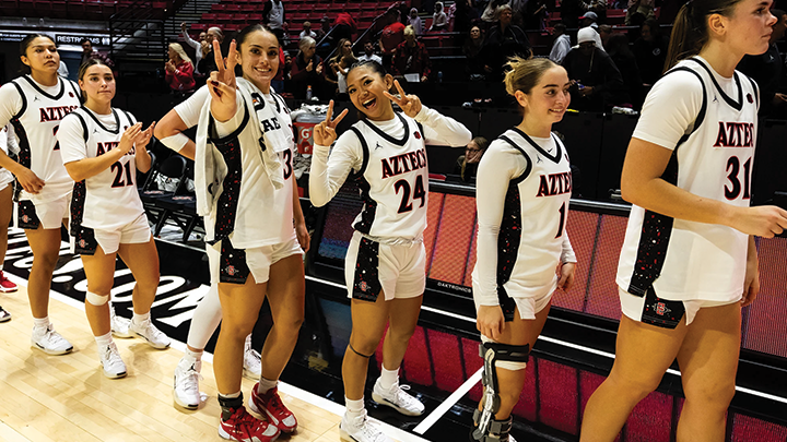 SDSU women's team players pose and smile toward the camera after their game.