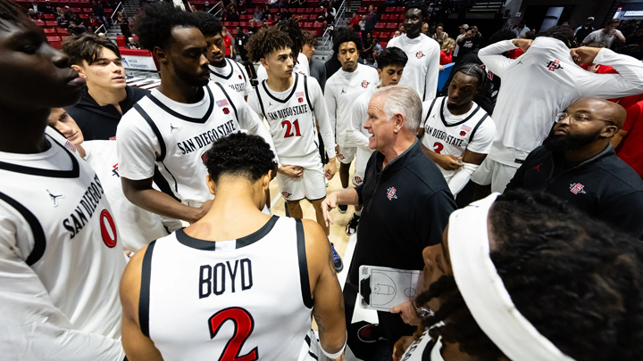 Aztecs basketball head coach Brian Dutcher gathers the team on the court for a quick huddle during a game