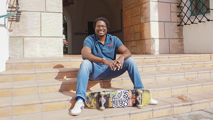 Neftalie Williams is photographed with his skateboard and sitting on steps at SDSU's campus