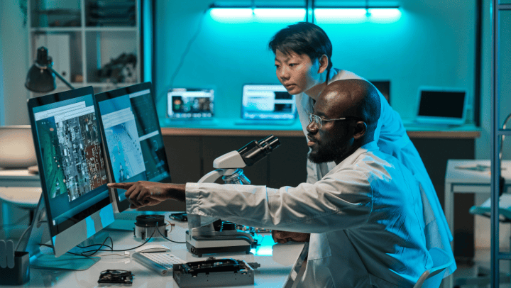 Two students observe data tracking on a monitor in a lab