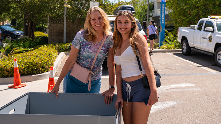 A student and her family smile at the camera during SDSU's move-in week.