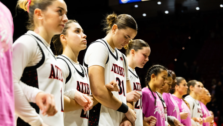 SDSU basketball players line up side-by-side on the court during the Star Spangled Banner