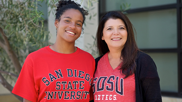 Two women stand shoulder to shoulder, both wearing tops marked for San Diego State University.
